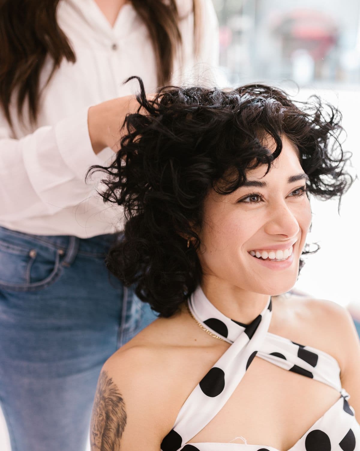 A stylist finishing a client’s curly haircut in the salon